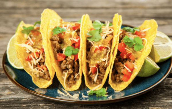 Four tacos with meat, cheese, and tomatoes.